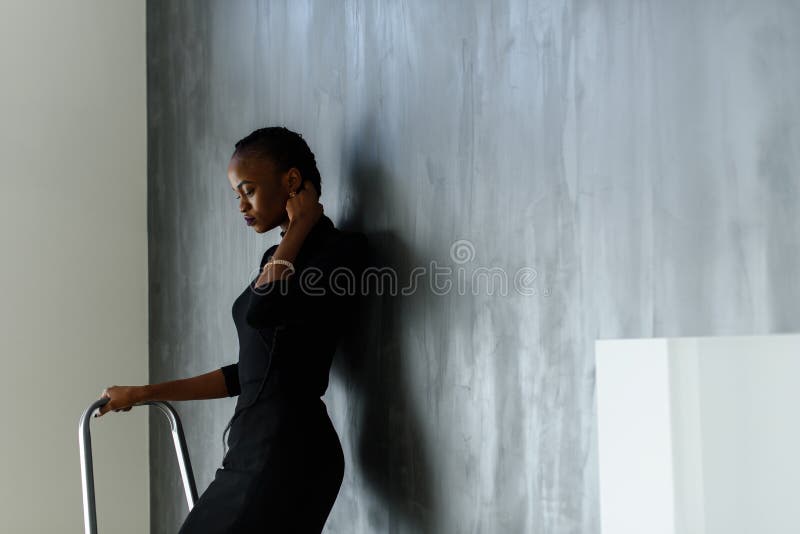 Side view of pretty african or black american woman touching her thick plait on dark studio background