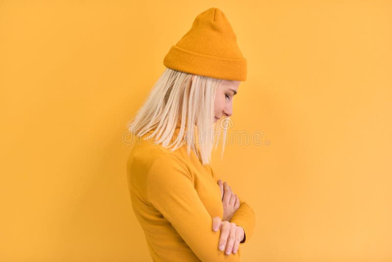 Side view of pretty blonde hair woman wears yellow clothes, hat, posing on yellow studio background. Copy space for advertisement royalty free stock image Side view of pretty blonde hair woman wears yellow clothes, hat, posing on yellow studio background. Copy space for advertisement royalty free stock image