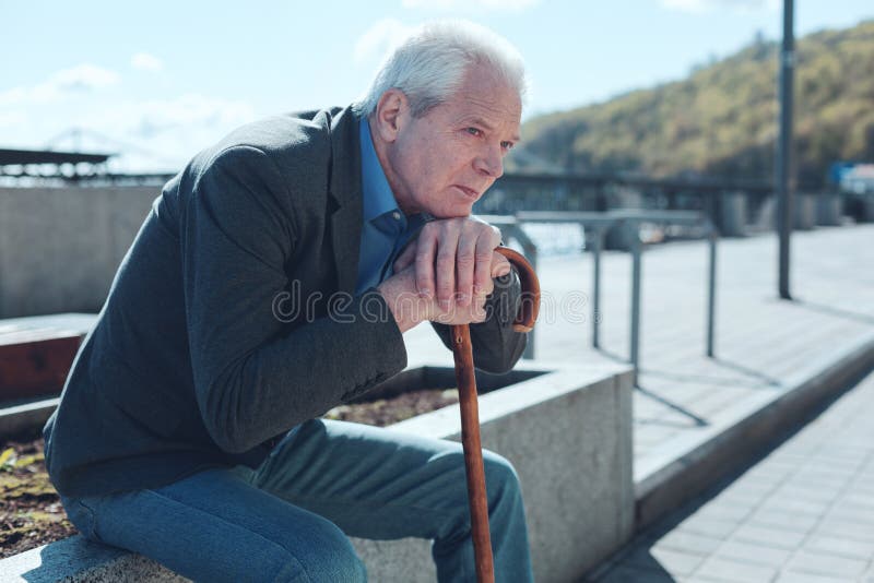 Time runs fast. Thoughtful retired man looking somewhere while sitting outdoors and feeling nostalgic while thinking of old good times. Time runs fast. Thoughtful retired man looking somewhere while sitting outdoors and feeling nostalgic while thinking of old good times.