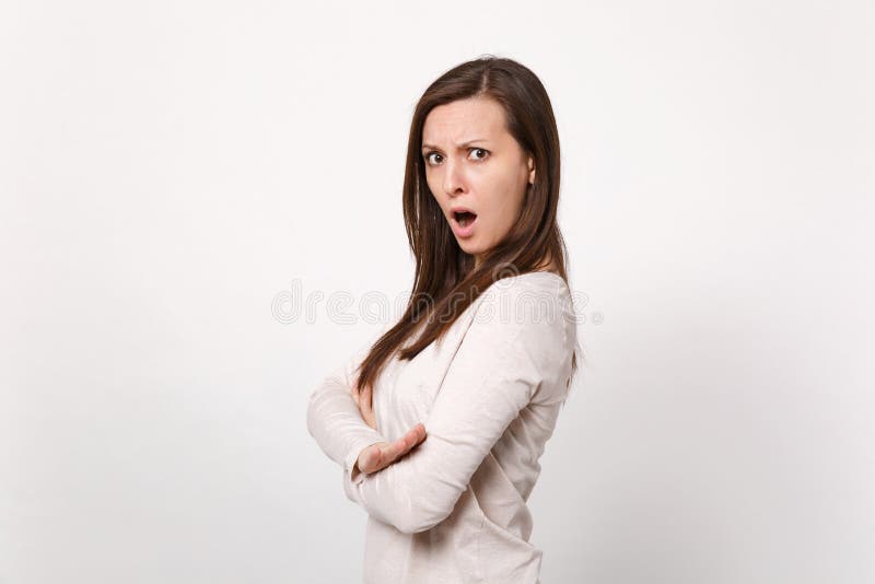 Side view of shocked irritated young woman in light clothes keeping mouth open, holding hands folded isolated on white stock image