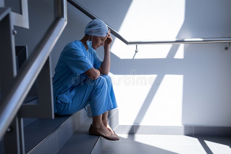 Upset female surgeon sitting on stair case in hospital royalty free stock images Upset female surgeon sitting on stair case in hospital royalty free stock images