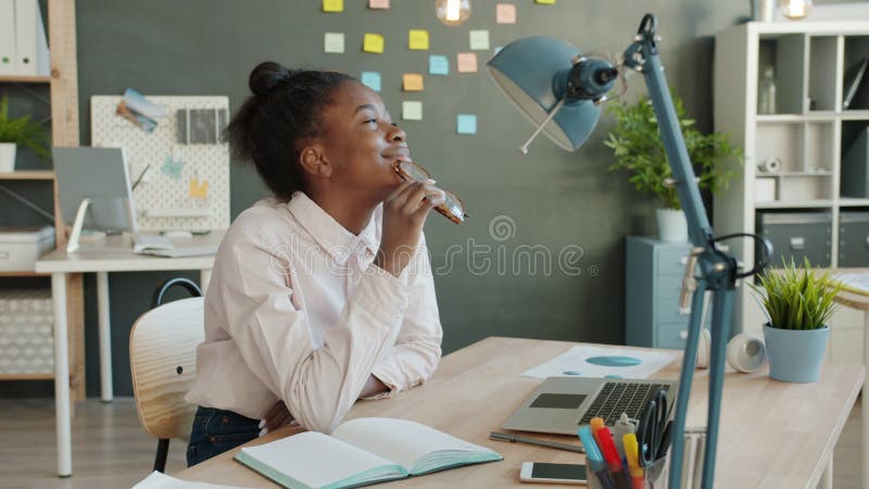 Side view of young African American office worker sitting at desk thinking then smiling