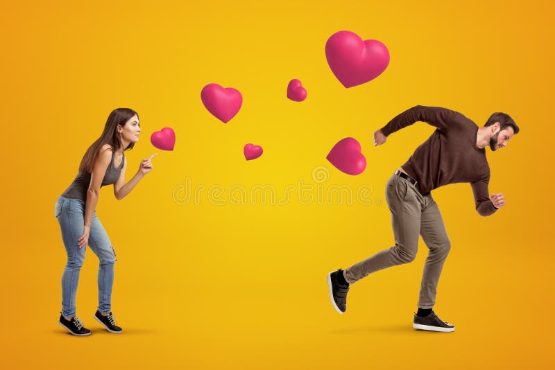 Side view of young girl following with her eyes young man who`s running away being chased by cute valentine hearts that