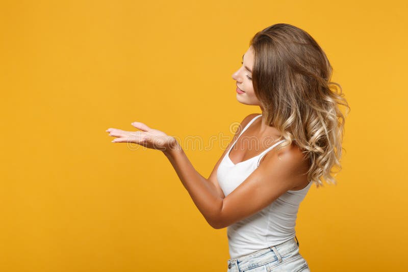 Side view of young woman in light casual clothes posing isolated on yellow orange background, studio portrait. People royalty free stock photography