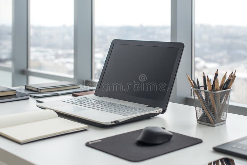 Sideview of office desktop with blank laptop and various tools.