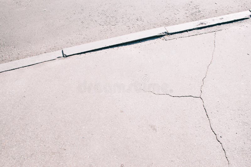 Sidewalk asphalt road with cracks. Old worn and cracked footpath close-up, gray urban background