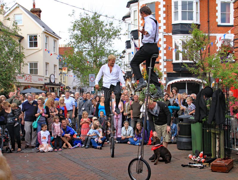 SIDMOUTH, DEVON, ENGLAND - 5. AUGUST 2012: Zwei Straßenjongleure und -entertainer führen im Marktplatz zu einem anerkennenden dur lizenzfreies stockfoto SIDMOUTH, DEVON, ENGLAND - 5. AUGUST 2012: Zwei Straßenjongleure und -entertainer führen im Marktplatz zu einem anerkennenden dur lizenzfreies stockfoto
