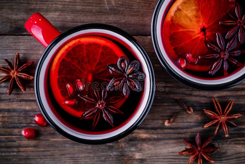 A sidra de maçã temperada da romã ferventou com especiarias a sangria do vinho em umas canecas vermelhas no fundo de madeira fotos de stock royalty free A sidra de maçã temperada da romã ferventou com especiarias a sangria do vinho em umas canecas vermelhas no fundo de madeira fotos de stock royalty free