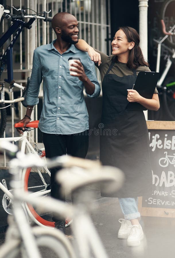 Sie denkt, der Chef sei. eine vollständige Aufnahme von zwei jungen Unternehmern, die während des Aufenthalts vor ihrem Fahrradlad stockfoto