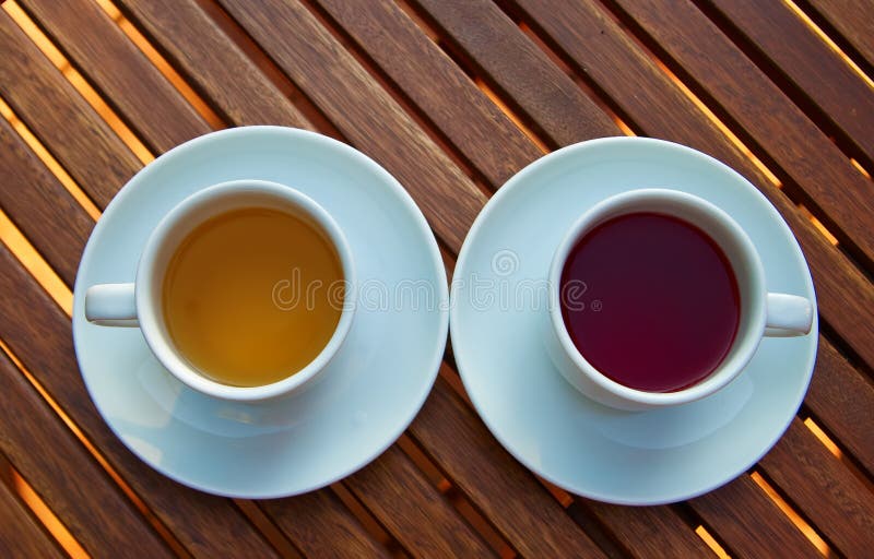 Two white cups with different kinds of tea - red fruit and yellow. Two white cups with different kinds of tea - red fruit and yellow