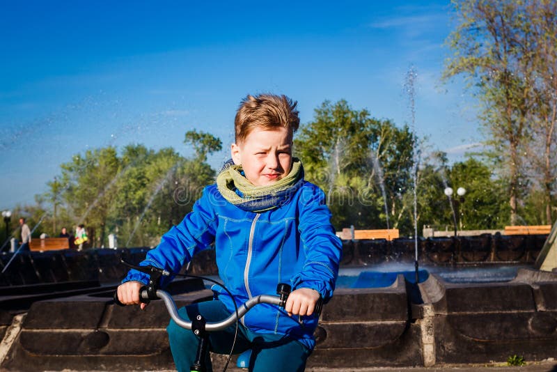 Siebenjähriger Junge, der ein Fahrrad im Stadt Park reitet Baby runzelt von der Sonne die Stirn stockbilder Siebenjähriger Junge, der ein Fahrrad im Stadt Park reitet Baby runzelt von der Sonne die Stirn stockbilder