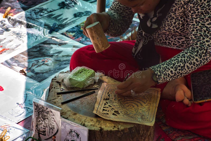 A local, cambodian woman is sitting and preparing colorful, traditional handcrafted pictures with khmer cultural motives royalty free stock photos A local, cambodian woman is sitting and preparing colorful, traditional handcrafted pictures with khmer cultural motives royalty free stock photos