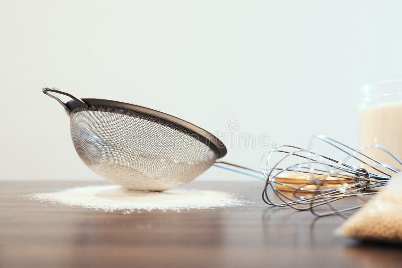 Sieve with flour and whisk on kitchen table on white background. Homemade baking cooking concept royalty free stock photos