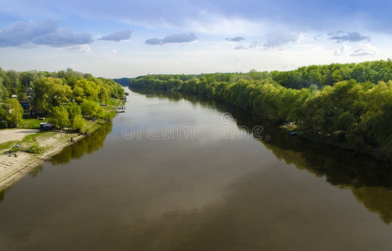 Siga um rio largo com as ?rvores verdes altas nos bancos na perspectiva do c?u azul fotos de stock royalty free Siga um rio largo com as ?rvores verdes altas nos bancos na perspectiva do c?u azul fotos de stock royalty free