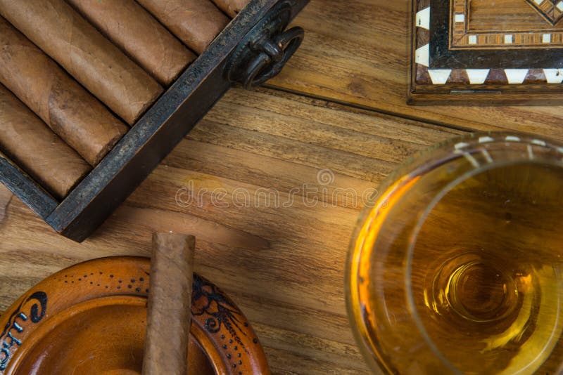 Cuban cigars and Rum or other alcohol in glass on table top view with vintage wooden background. Cuban cigars and Rum or other alcohol in glass on table top view with vintage wooden background