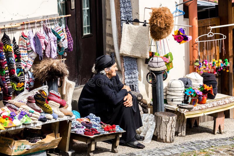 Sighnaghi, Georgia - 10 de junio de 2016: Vendedor mayor de la mujer que vende calcetines, los deslizadores de lana y los recuerd foto de archivo libre de regalías Sighnaghi, Georgia - 10 de junio de 2016: Vendedor mayor de la mujer que vende calcetines, los deslizadores de lana y los recuerd foto de archivo libre de regalías