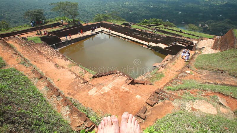 SIGIRIYA, ШРИ-ЛАНКА - ФЕВРАЛЬ 2014: Взгляд верхней части крепости утеса в Sigiriya с ногами человека в визировании Sigiriya старо