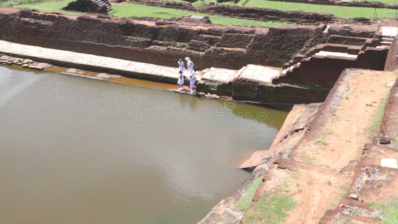 SIGIRIYA, ШРИ-ЛАНКА - ФЕВРАЛЬ 2014: Взгляд девушек школы проходя мимо на Sigiriya, старый дворец расположенный в центральном Mata