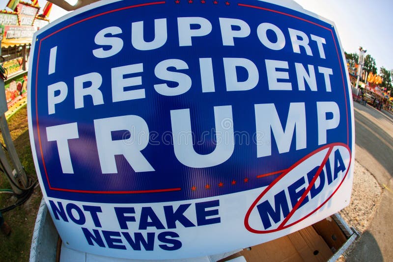 Lawrenceville, GA, USA - September 22, 2017: A sign reading `I support President Trump, not fake news media` sits on a vendor`s cart at the Gwinnett County Fair, on September 22, 2017 in Lawrenceville, GA. Lawrenceville, GA, USA - September 22, 2017: A sign reading `I support President Trump, not fake news media` sits on a vendor`s cart at the Gwinnett County Fair, on September 22, 2017 in Lawrenceville, GA.