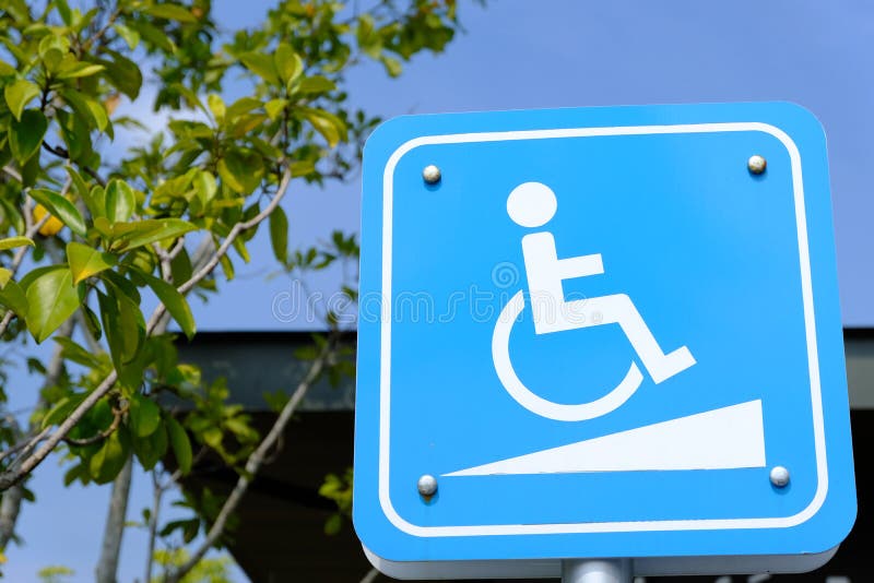 Signe de manière de pente pour des personnes de fauteuil roulant sur le fond de ciel bleu - stationnement handicapé image stock Signe de manière de pente pour des personnes de fauteuil roulant sur le fond de ciel bleu - stationnement handicapé image stock