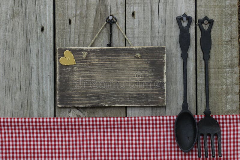Signe en bois vide avec la nappe de guingan, le coeur d'or et la cuillère et la fourchette rouges de fonte avec le fond en bois photographie stock libre de droits Signe en bois vide avec la nappe de guingan, le coeur d'or et la cuillère et la fourchette rouges de fonte avec le fond en bois photographie stock libre de droits