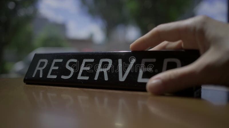 Signe réservé définissant sur la table de café avec la fenêtre vue ville. La table est réservée. La main femelle a mis sur l'ongle clips vidéos