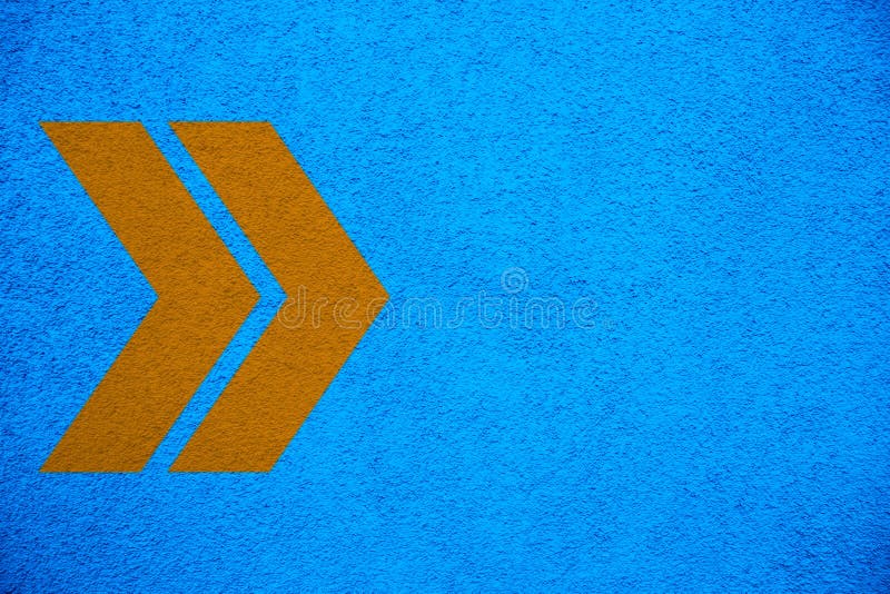 Signes jaune-orange de flèches dirigeant la bonne direction au-dessus du fond approximatif de mur de stuc bleu lumineux intense d images libres de droits Signes jaune-orange de flèches dirigeant la bonne direction au-dessus du fond approximatif de mur de stuc bleu lumineux intense d images libres de droits