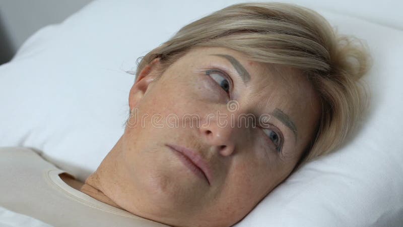 Signora anziana che sveglia nell'ospedale dopo l'anestesia della chirurgia, problema sanitario
