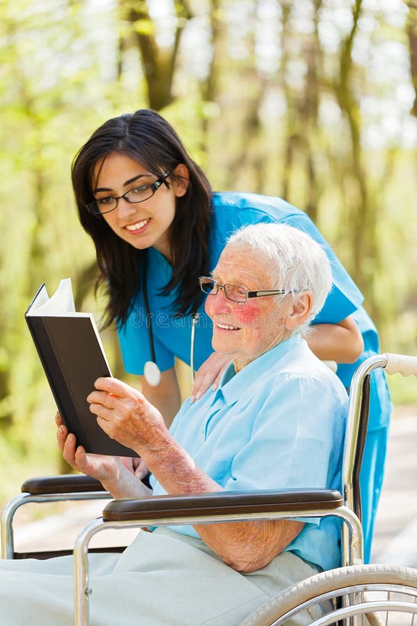 Signora anziana nella lettura della sedia a rotelle immagini stock libere da diritti Signora anziana nella lettura della sedia a rotelle immagini stock libere da diritti