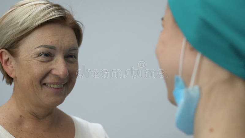 Signora anziana sorridente che abbraccia infermiere, remissione dopo la malattia mortale, buone notizie