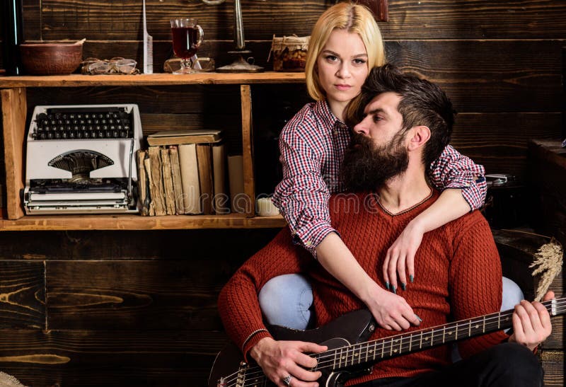 Signora ed uomo con la barba sulla chitarra vaga degli abbracci e dei giochi dei fronti Le coppie nell'interno d'annata di legno fotografie stock Signora ed uomo con la barba sulla chitarra vaga degli abbracci e dei giochi dei fronti Le coppie nell'interno d'annata di legno fotografie stock