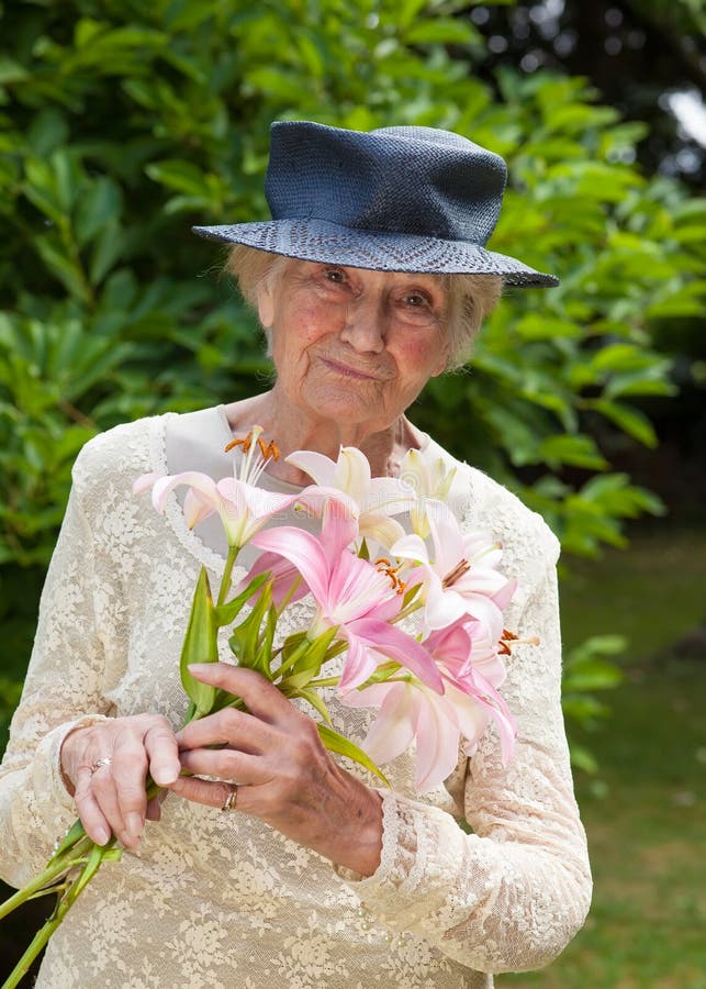 Signora senior che tiene un mazzo dei gigli freschi fotografie stock libere da diritti