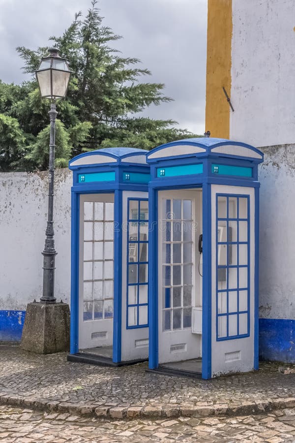 Sikt av blåa retro telefonbås, i gata av den medeltida byn av Obidos arkivfoton Sikt av blåa retro telefonbås, i gata av den medeltida byn av Obidos arkivfoton