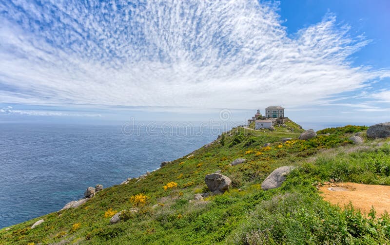 Sikt av udde Finisterre, Galicia, Spanien med fyren under en molnig blå himmel royaltyfri fotografi Sikt av udde Finisterre, Galicia, Spanien med fyren under en molnig blå himmel royaltyfri fotografi