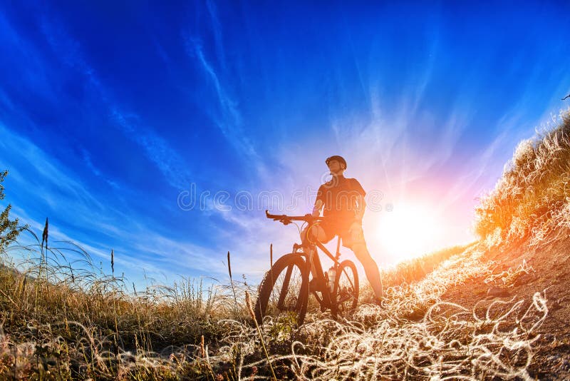Sikt för låg vinkel av cyklistanseendet med mountainbiket på slinga på soluppgång royaltyfri bild Sikt för låg vinkel av cyklistanseendet med mountainbiket på slinga på soluppgång royaltyfri bild