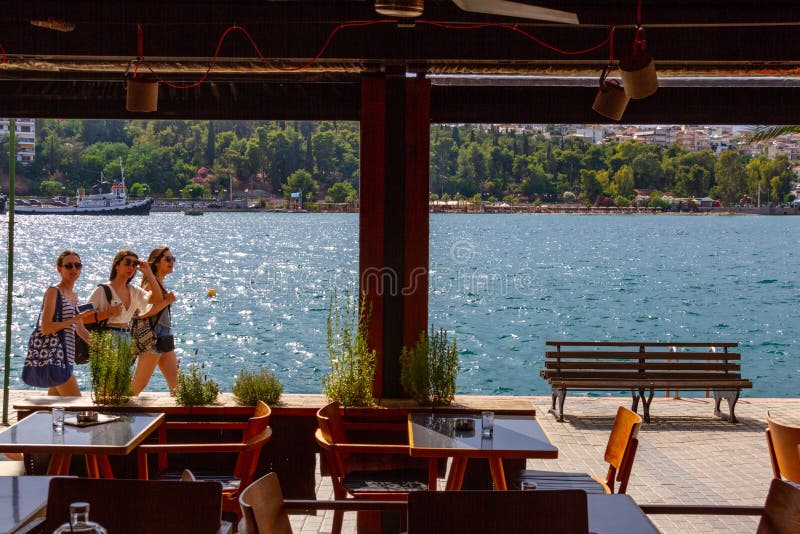 Sikt via kaféfönster av tre flickor som promenerar promenaden i chalcisen, Grekland royaltyfri bild Sikt via kaféfönster av tre flickor som promenerar promenaden i chalcisen, Grekland royaltyfri bild