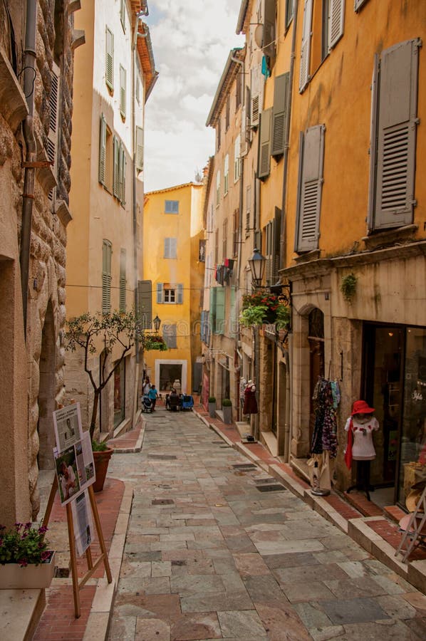 Sikten av den smala gatan och byggnader med shoppar i Grasse arkivfoton Sikten av den smala gatan och byggnader med shoppar i Grasse arkivfoton