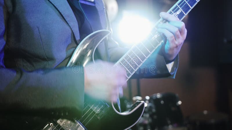 sikten för närbilden 4k av mannen räcker att spela gitarren med en medlare Gitarristen utför på etapp