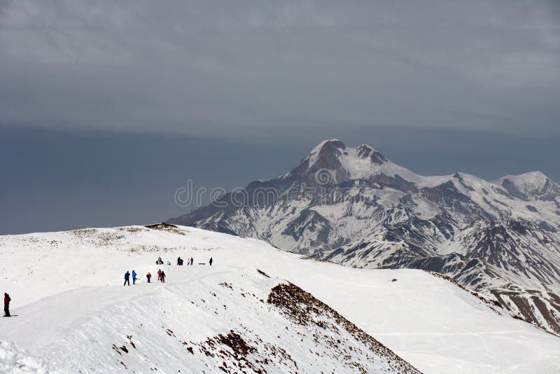 Sikten skidar på lutningen och härliga berg i afton Skidar semesterorten Gudauri, Kaukasus berg, Georgia royaltyfri foto Sikten skidar på lutningen och härliga berg i afton Skidar semesterorten Gudauri, Kaukasus berg, Georgia royaltyfri foto