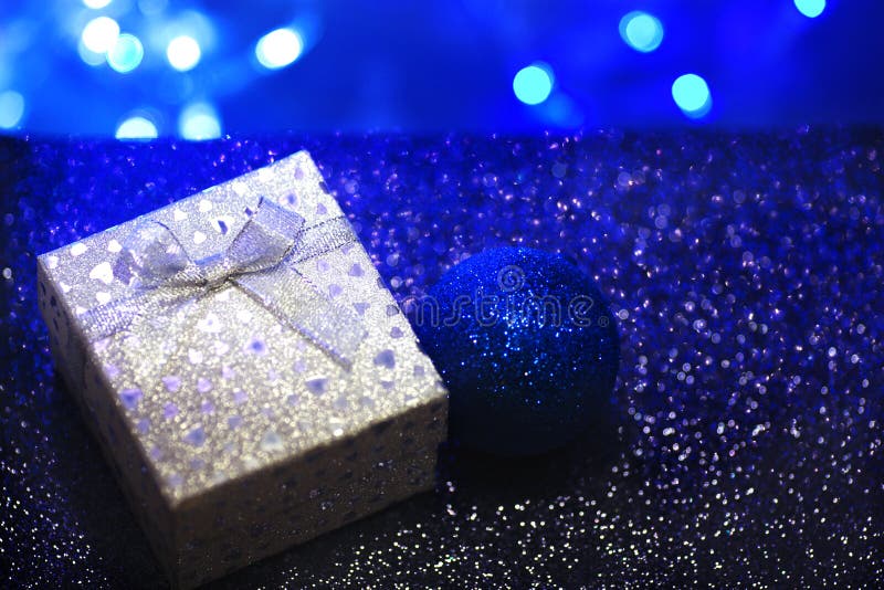 Silberne Geschenkbox mit einem Bogen und Herzen auf einem dunkelblauen unscharfen Hintergrund stockfotos Silberne Geschenkbox mit einem Bogen und Herzen auf einem dunkelblauen unscharfen Hintergrund stockfotos