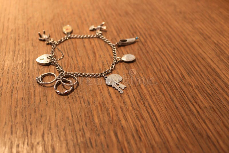 Silbernes Charmearmband auf einem verkratzten hölzernen Hintergrund stockfotografie Silbernes Charmearmband auf einem verkratzten hölzernen Hintergrund stockfotografie