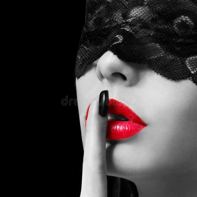 Silenzio. La donna sexy con il dito sulla sua mostra rossa delle labbra zittisce. Ragazza erotica con la maschera del pizzo sopra