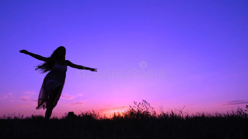 Silhouet die van jong meisje bij roze zonsondergang dansen