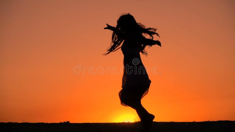 Silhouet die van jong meisje bij zonsondergang dansen