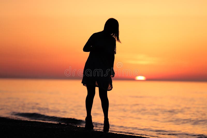 Silhouet van een dame die op het strand lopen