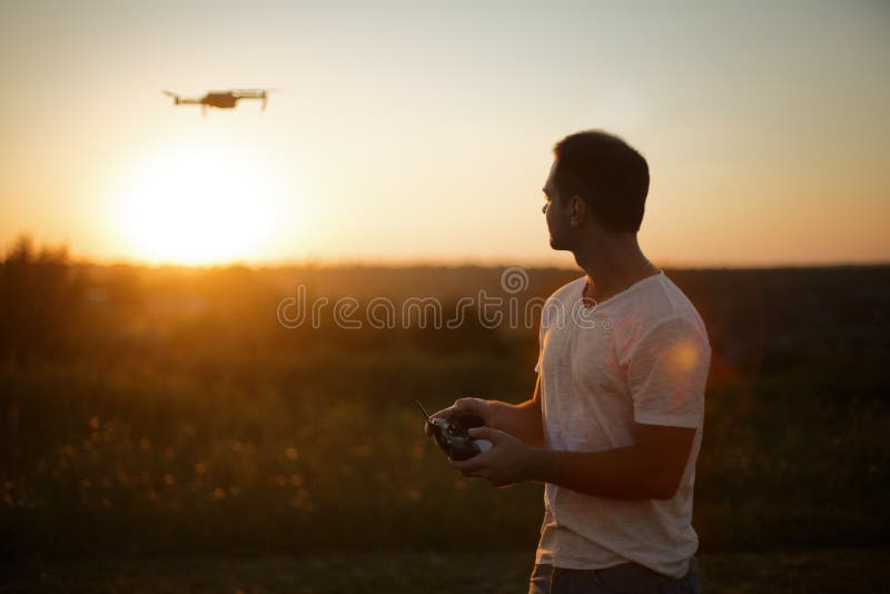Silhouet van een mens het loodsen hommel in de lucht met een ver controlemechanisme in zijn handen op zonsondergang Proef neemt l royalty-vrije stock fotografie Silhouet van een mens het loodsen hommel in de lucht met een ver controlemechanisme in zijn handen op zonsondergang Proef neemt l royalty-vrije stock fotografie