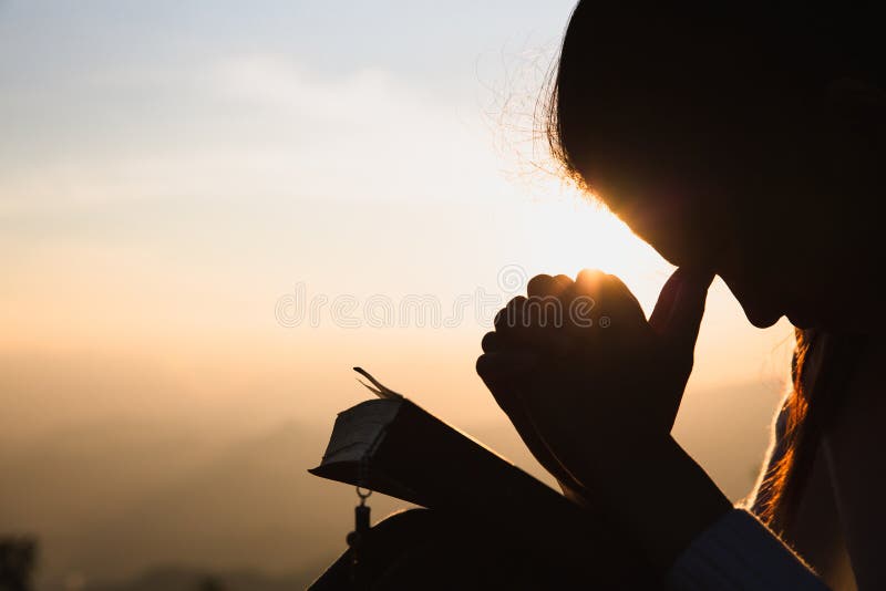 Silhouet van een vrouw met handen in het zonsondergangconcept worden opgeheven voor het gebed en het prijzen van religieuze concep