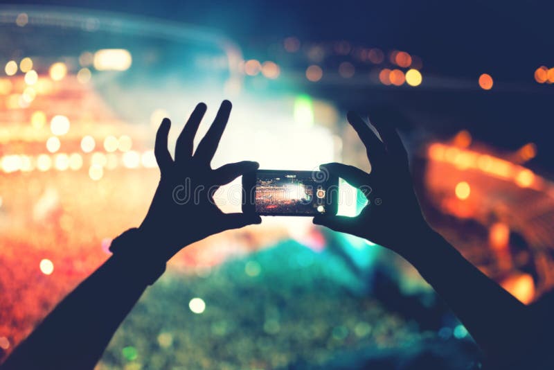 Silhouet van handen die cameratelefoon met behulp van om beelden en video's bij pop overleg, festival te nemen