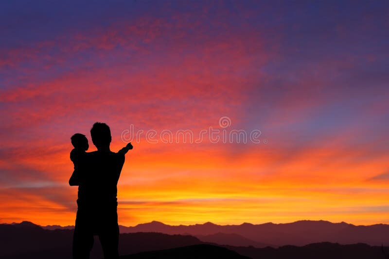 The silhouette of family (Father and child) watching the sunrise and hand finger point to sun with mountain. The silhouette of family (Father and child) watching the sunrise and hand finger point to sun with mountain