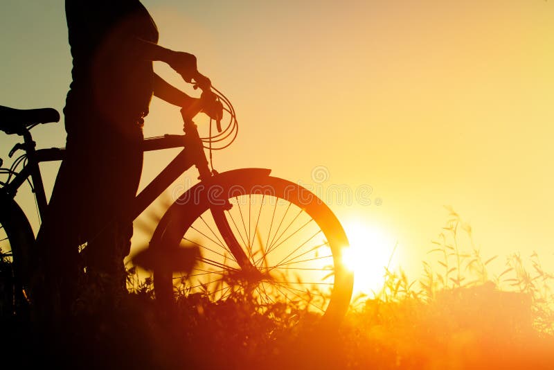 Silhouet van jonge vrouwen berijdende fiets bij zonsondergang royalty-vrije stock foto Silhouet van jonge vrouwen berijdende fiets bij zonsondergang royalty-vrije stock foto